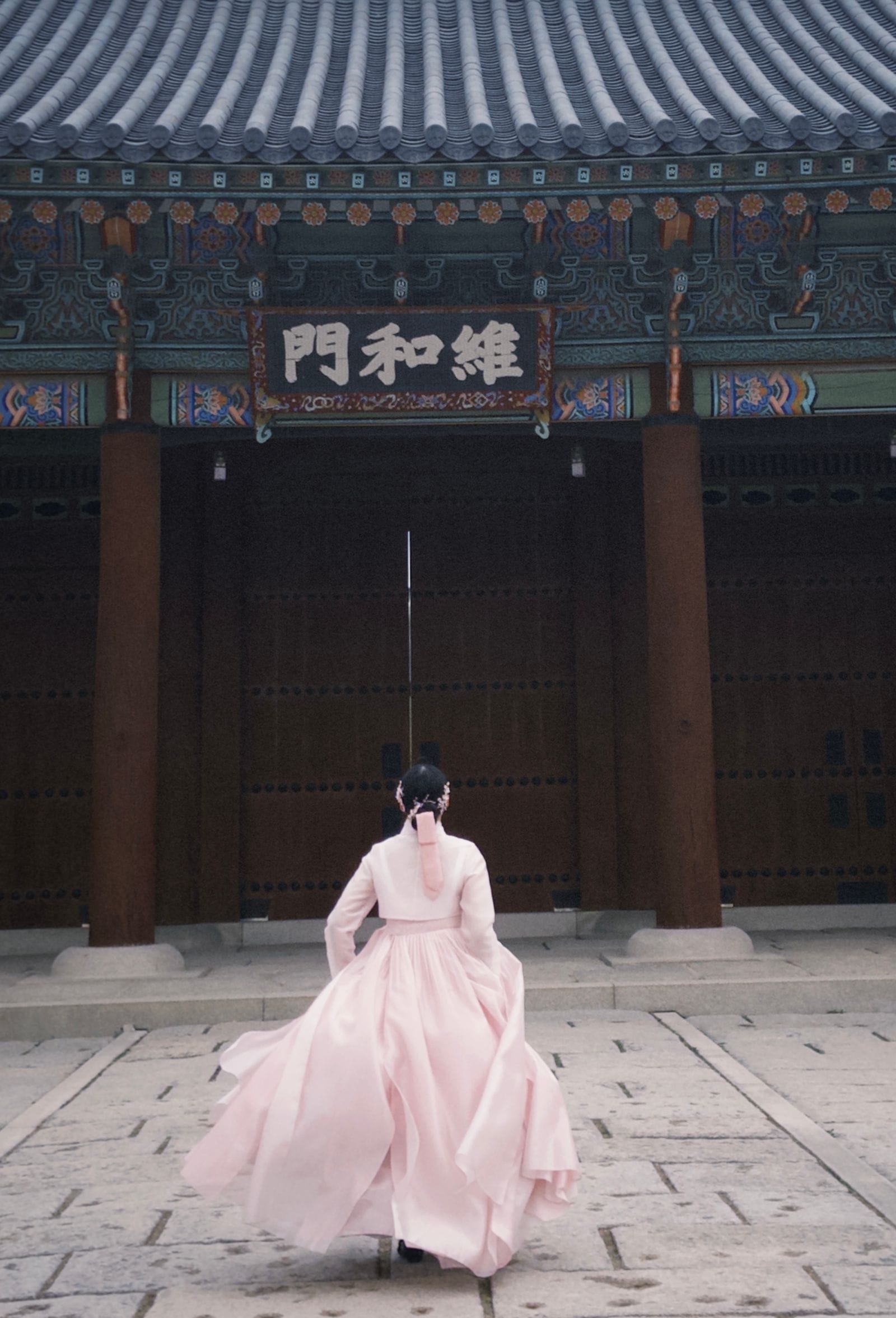 A woman in a pink hanbok at a historic Korean palace, the classic reason for hanbok rental in Seoul