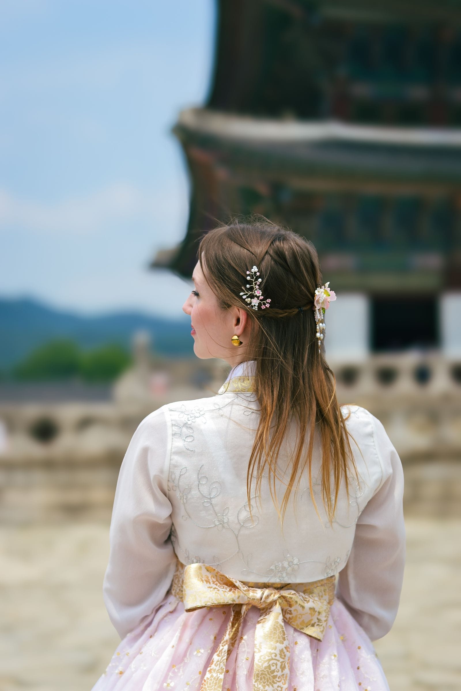 A woman in traditional hanbok admiring a palace in South Korea