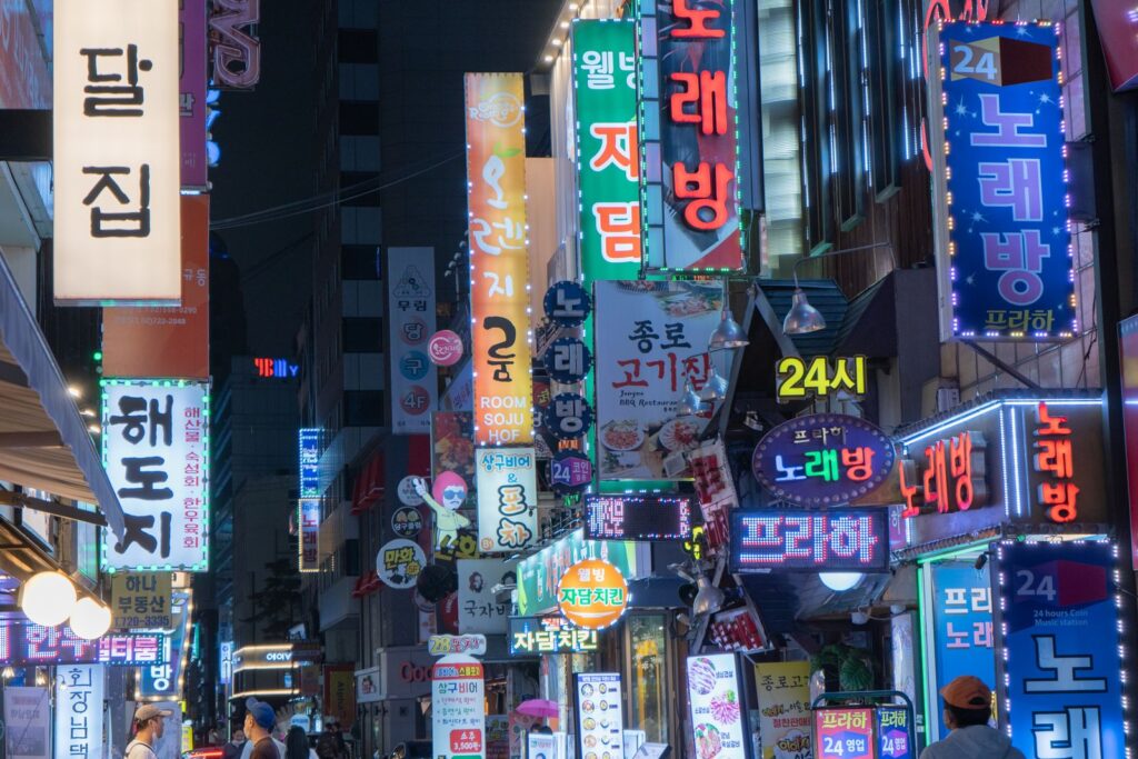 Where to Stay in Seoul: Best Neighborhoods for First-Time Visitors Neon signs lighting up Myeongdong shopping street in Seoul at night