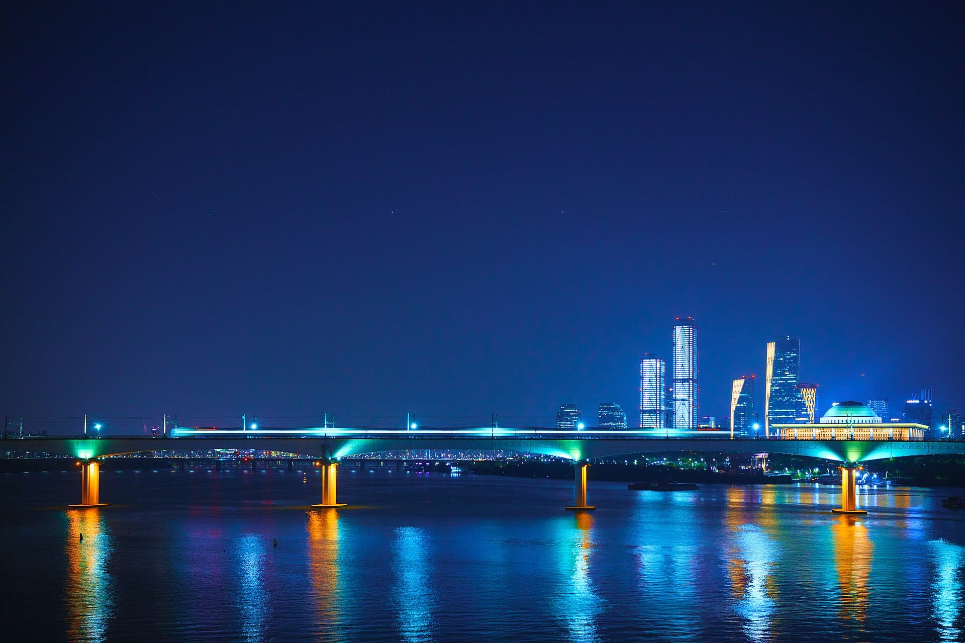 Hangang River Festival 2026: Seoul's Free Summer Event (Aug 1–16) An illuminated railway bridge over the Han River in Seoul at night, near the festival's riverside parks