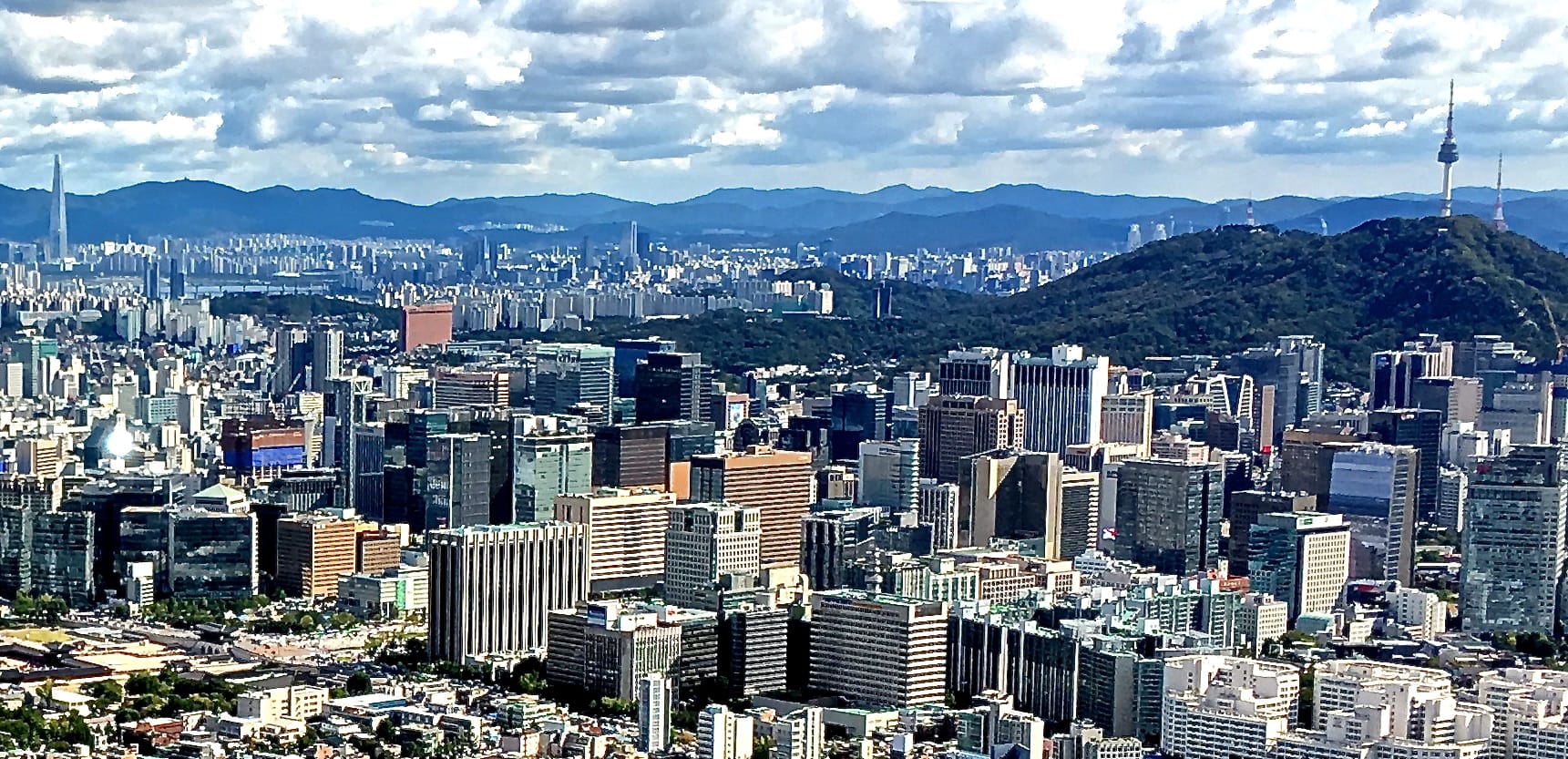 Seoul travel guide hero — the city skyline with Lotte World Tower and Namsan Tower at dusk