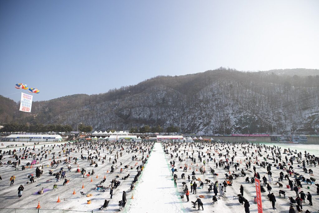 Crowds ice fishing through holes drilled in the frozen Hwacheon Stream at the Hwacheon Sancheoneo Ice Festival in Korea