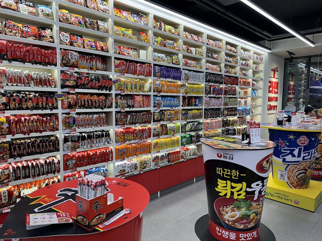A 24-hour Korean convenience store shelf stacked with cup ramyeon and instant noodles
