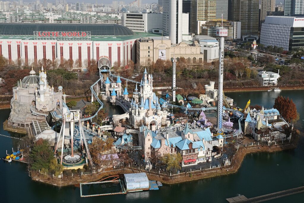 Lotte World Seoul seen from above, with the Magic Island castle on Seokchon Lake and the indoor Adventure dome behind it